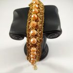 Bracciale realizzato ad uncinetto in filato gioiello color oro e mezzi cristalli rosati