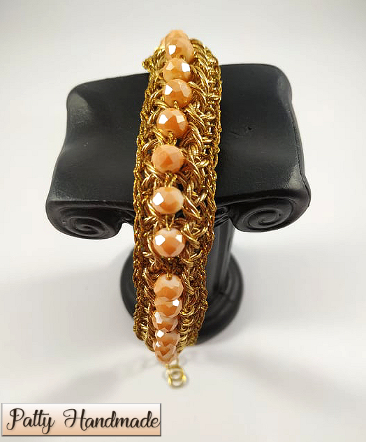 Bracciale realizzato ad uncinetto in filato gioiello color oro e mezzi cristalli rosati