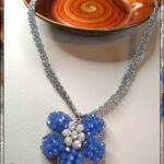 Collana con ciondolo realizzata ad uncinetto con filato gioiello di colore argento e mezzi cristalli azzurri