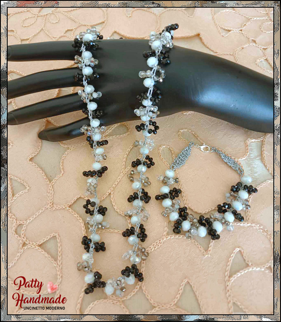 Set di collana e bracciale realizzato interamente a mano ad uncinetto, con perle bianche e mezzi cristalli di colore argento e nero
